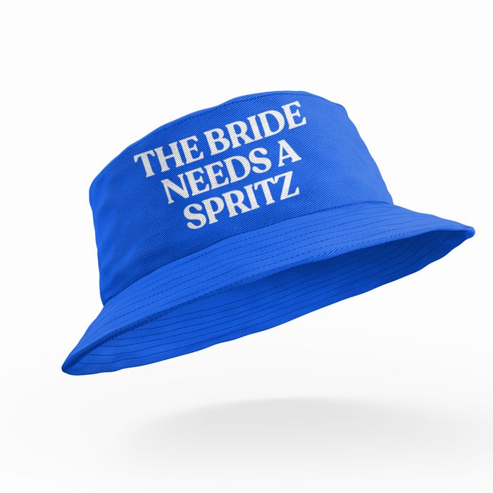 Blue bucket hat with white text 'THE BRIDE NEEDS A SPRITZ' on a white background